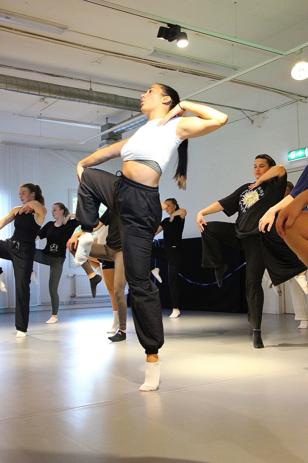 Zeynep lyfter knäet högt i ett kraftfullt danssteg i studion